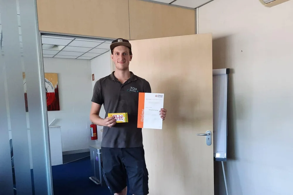 Medewerker van De Bresser met zijn diploma van het Verhuiscollege op kantoor