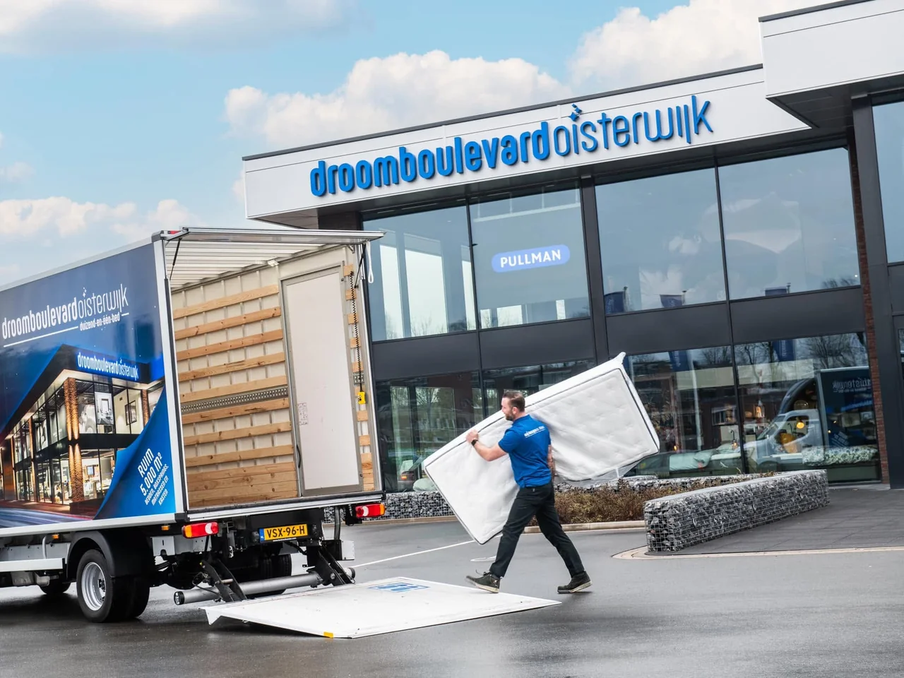 Man draagt een matras van de laadklep van een vrachtwagen naar de winkel van Droomboulevard Oisterwijk