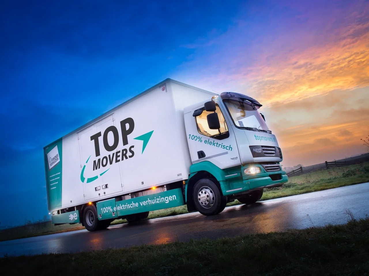 Witte elektrische verhuiswagen van Top Movers op de weg bij zonsondergang