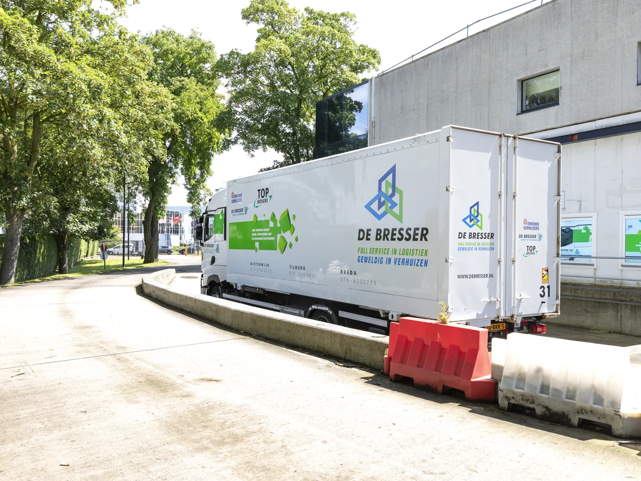 Vrachtwagen met oplegger van De Bresser bij het laadperron van een bedrijfspand