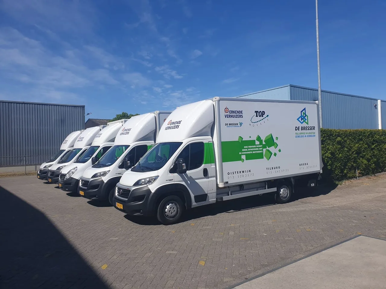 Rij witte vrachtwagens van De Bresser met de opdruk full service in logistiek op het eigen terrein
