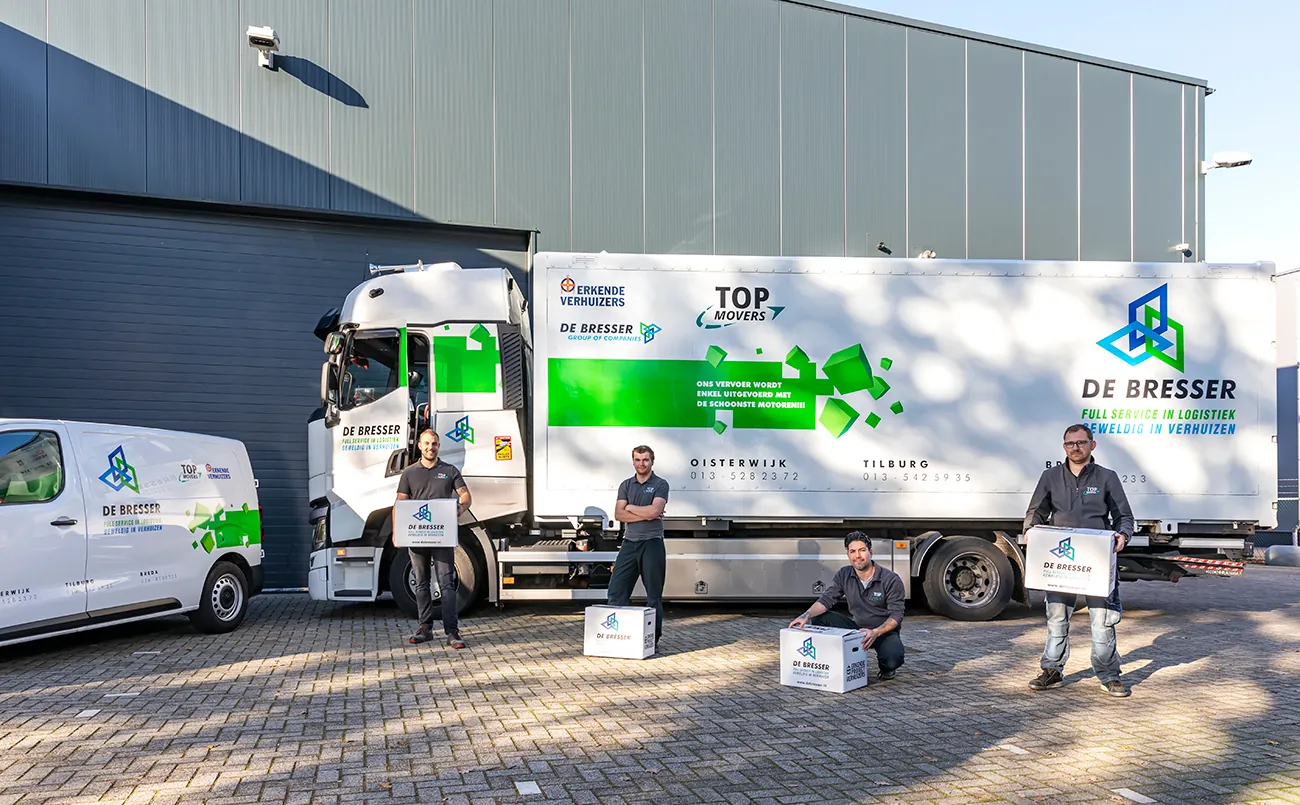 Medewerkers van De Bresser met verhuisdozen voor een vrachtwagen en een bus van De Bresser